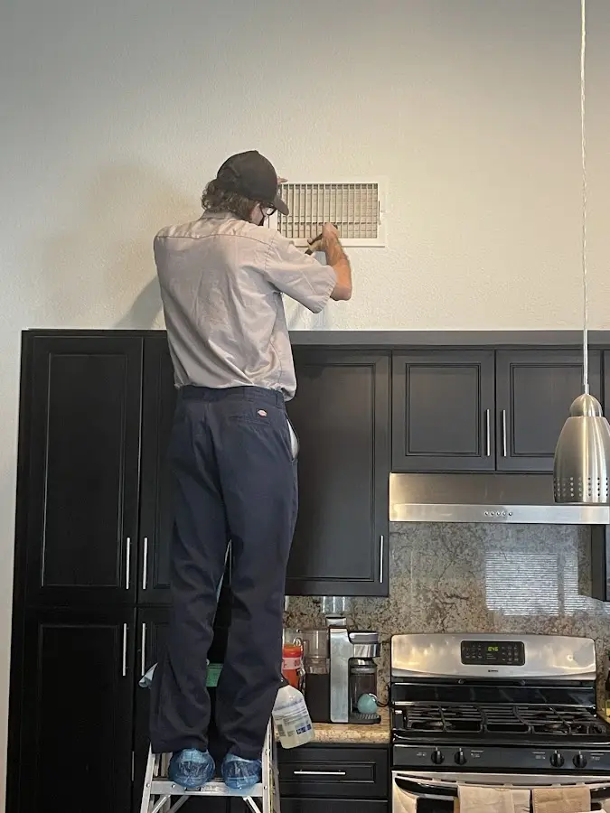 Technician inspecting an air vent during HVAC service in East Allen